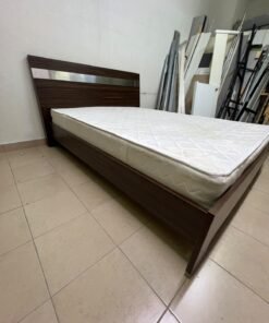 A dark brown wooden double bed featuring a headboard accented with a silver metal strip, and equipped with a white padded mattress.