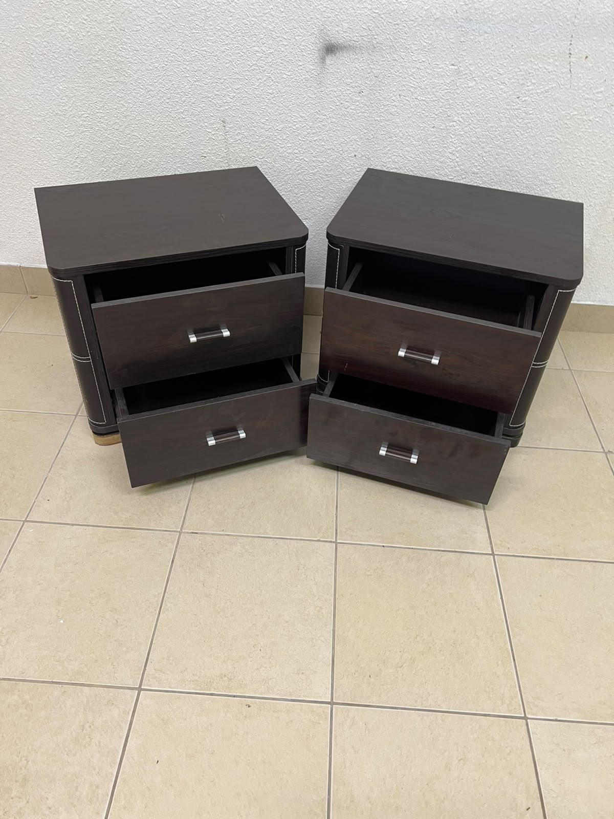 Two dark brown wooden bedside tables (nightstands) featuring two drawers and curved corners, accented with contrasting white stitching and silver-colored metal drawer handles. - Image 2