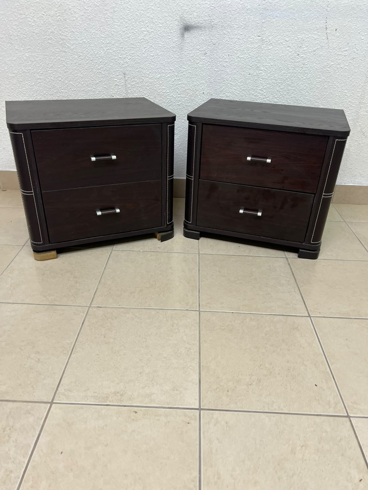 Two dark brown wooden bedside tables (nightstands) featuring two drawers and curved corners, accented with contrasting white stitching and silver-colored metal drawer handles. - Image 4