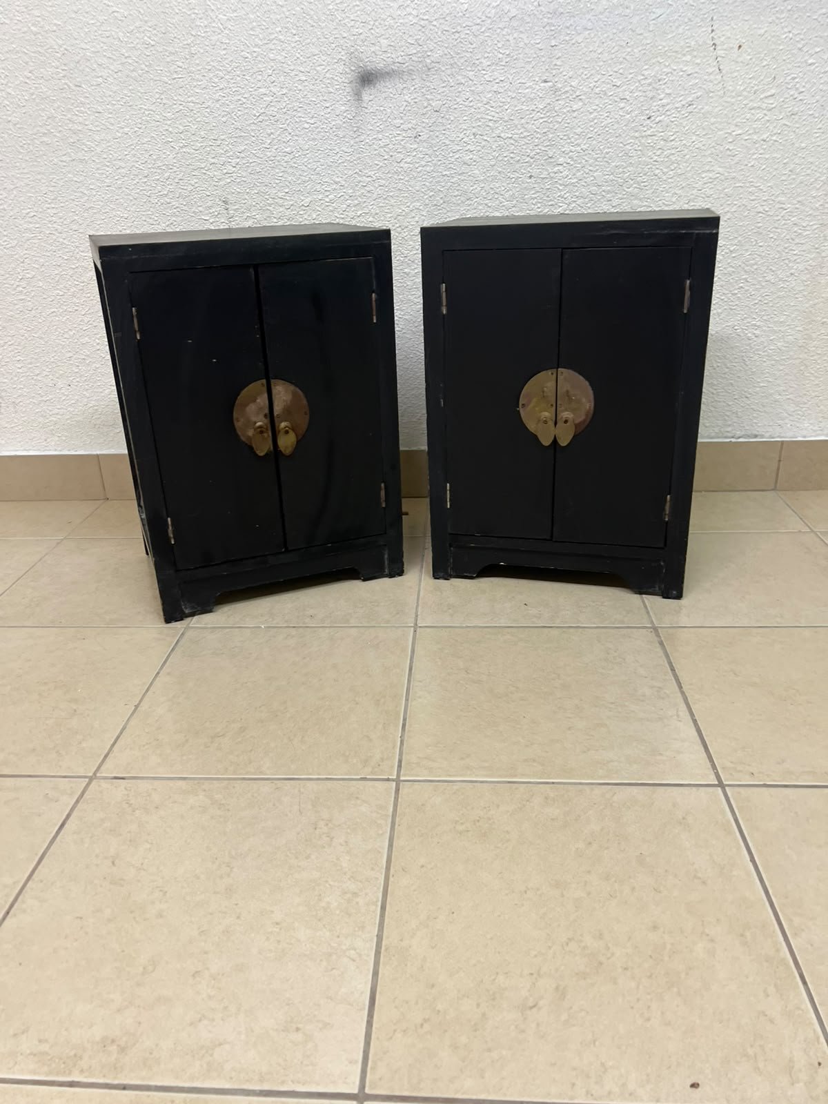 Two bedside cabinets featuring an Asian design or Oriental-inspired style, crafted from wood with a black finish and fitted with traditional round brass handles.