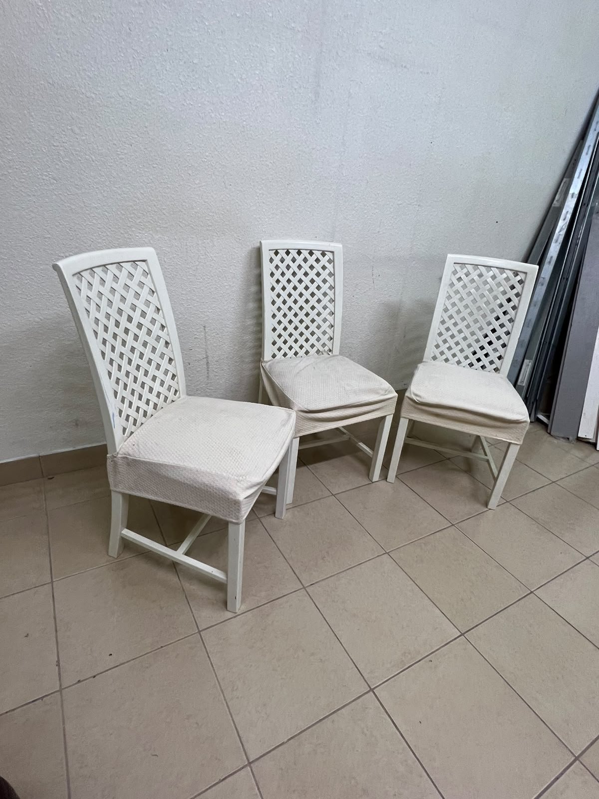 A set of white wooden chairs featuring a woven-mesh backrest design and white seat covers. - Image 4