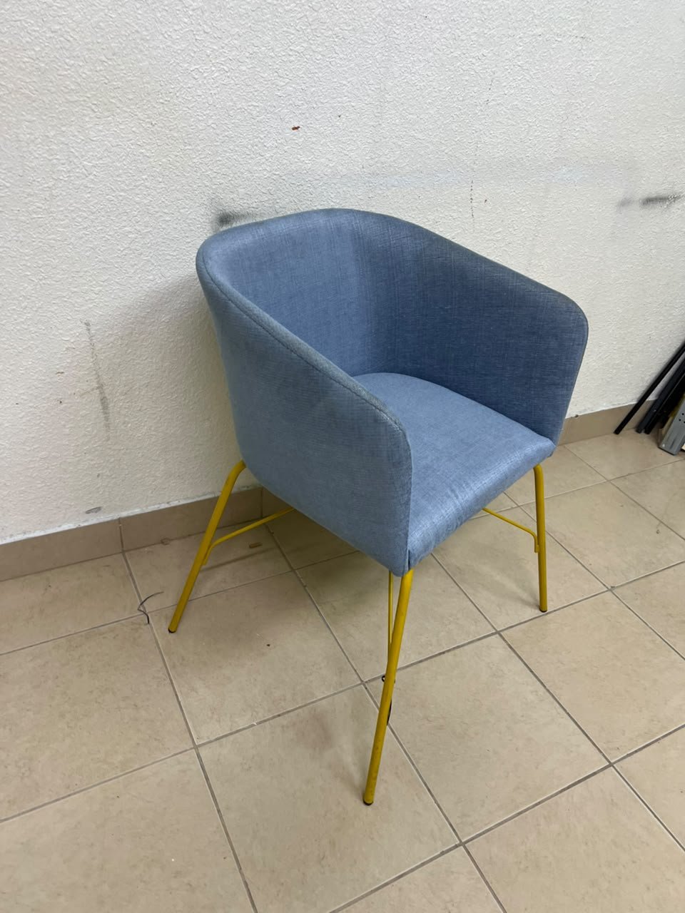 A modern barrel-style armchair or upholstered dining chair, featuring light blue fabric upholstery and slender yellow metal legs. - Image 2