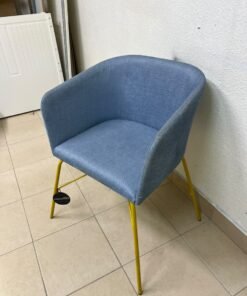 A modern barrel-style armchair or upholstered dining chair, featuring light blue fabric upholstery and slender yellow metal legs. - Image 3