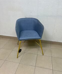 A modern barrel-style armchair or upholstered dining chair, featuring light blue fabric upholstery and slender yellow metal legs. - Image 4