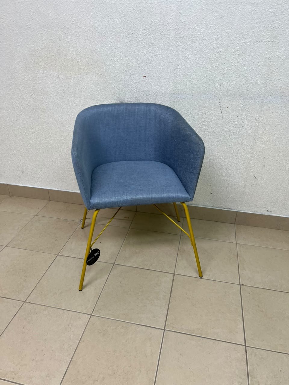 A modern barrel-style armchair or upholstered dining chair, featuring light blue fabric upholstery and slender yellow metal legs. - Image 4