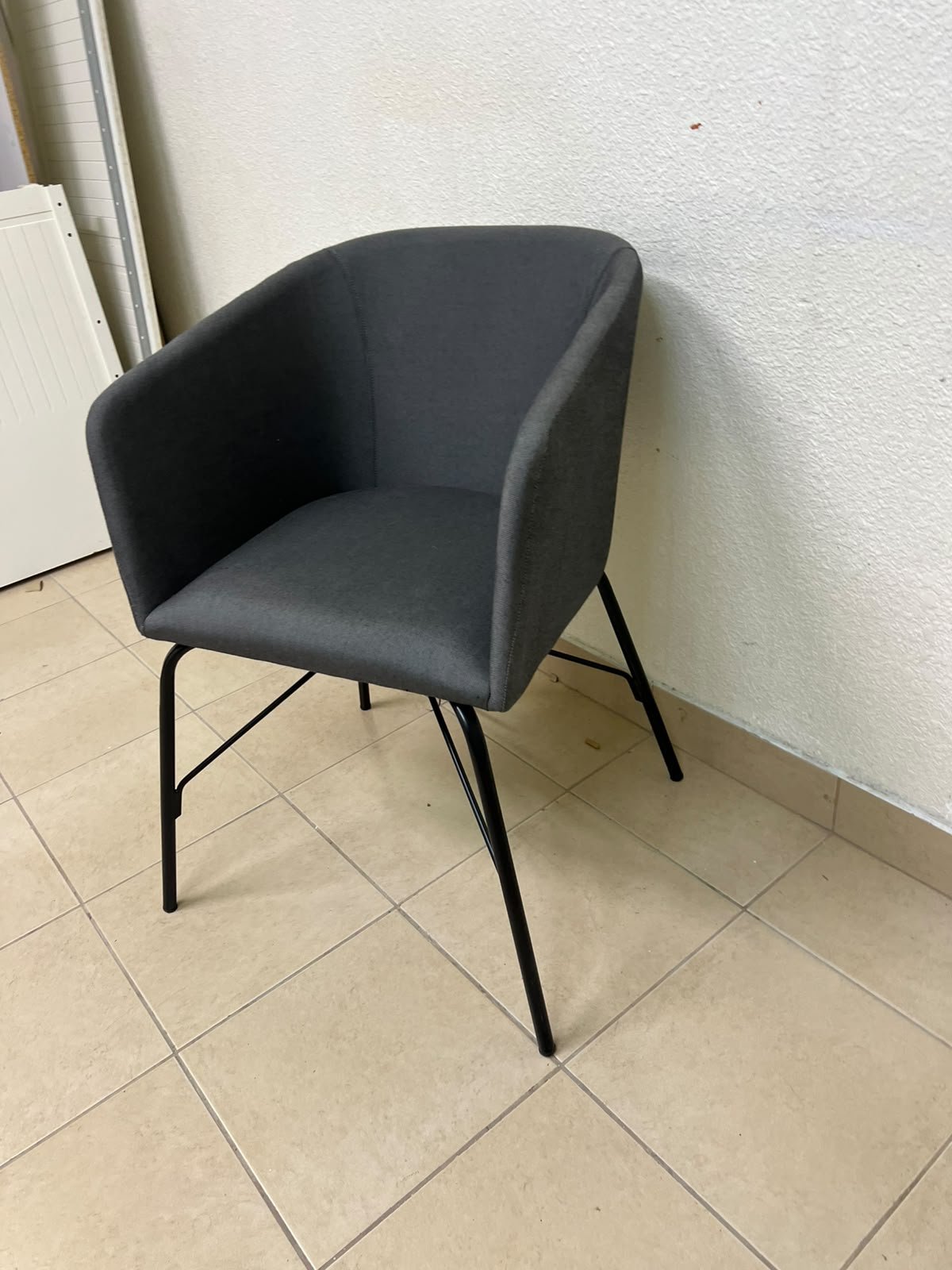 The chair shown in the picture looks similar to the TOSSBERG model from IKEA, made of dark gray fabric with black metal legs. - Image 3