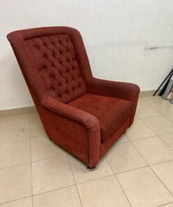 A classic-style armchair featuring a high, button-tufted backrest, upholstered in textured dark red fabric, and accented with metal nailhead trim along the edges.
