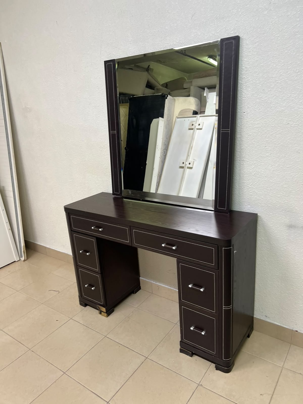 The image shows a brown wooden vanity table with an attached mirror and multiple drawers.