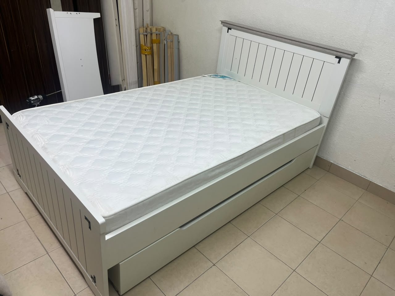 A white wooden single bed featuring a pull-out trundle bed underneath, with two matching padded mattresses. - Image 4