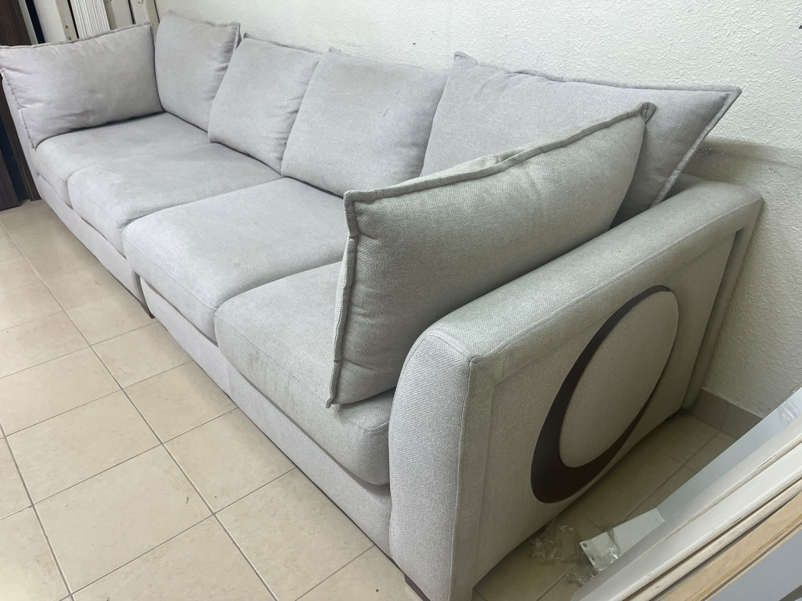 A modern sectional sofa upholstered in light gray fabric, featuring wide armrests with striking rounded details and matching, separate back cushions.