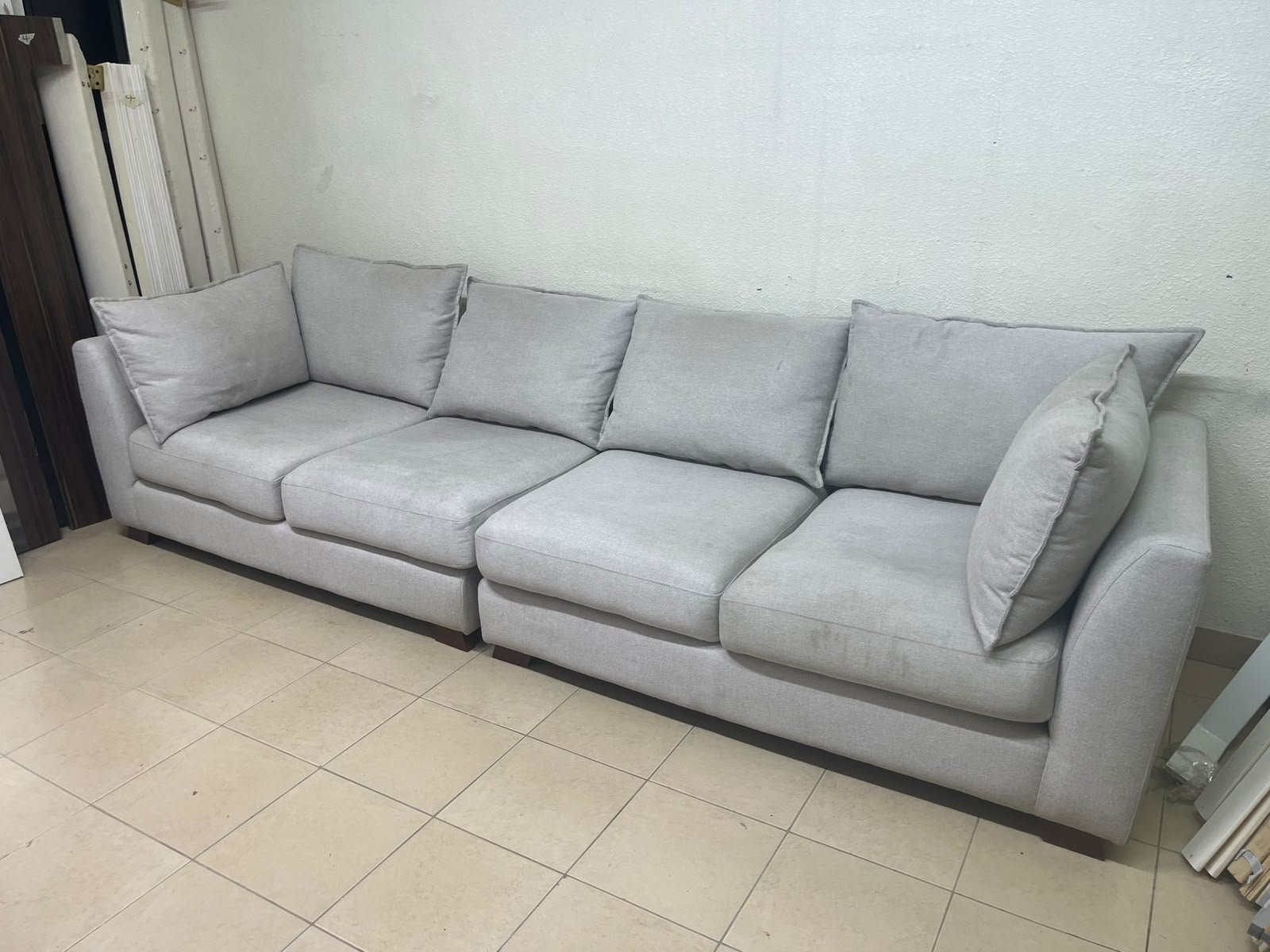 A modern sectional sofa upholstered in light gray fabric, featuring wide armrests with striking rounded details and matching, separate back cushions. - Image 4