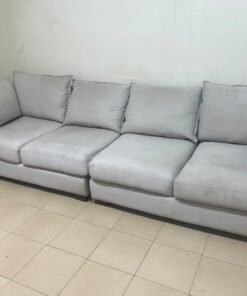 A modern sectional sofa upholstered in light gray fabric, featuring wide armrests with striking rounded details and matching, separate back cushions. - Image 7