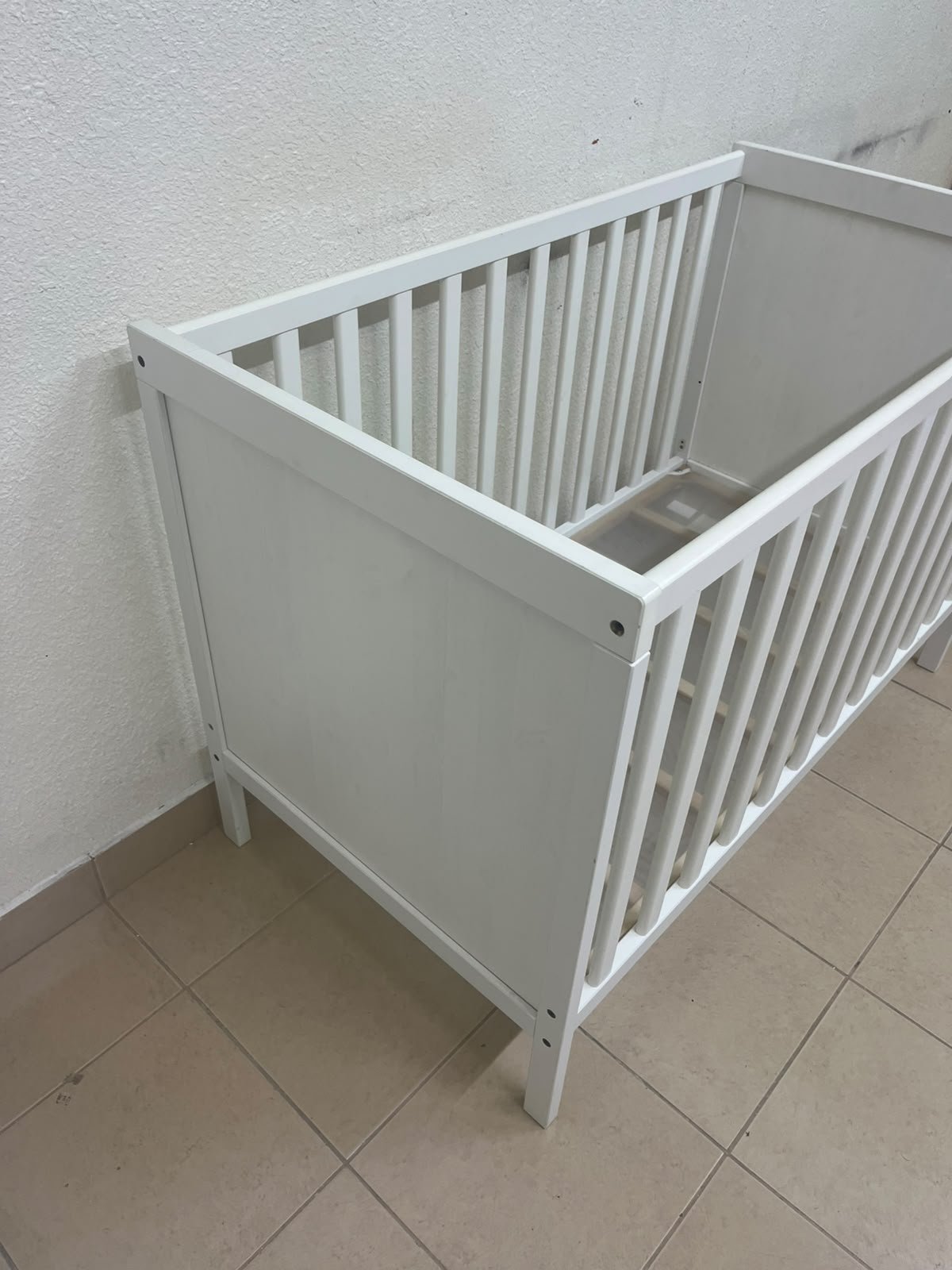 The white IKEA SUNDVIK crib (60x120 cm) features a sturdy wooden design and a bed base that can be adjusted to two different heights. - Image 6