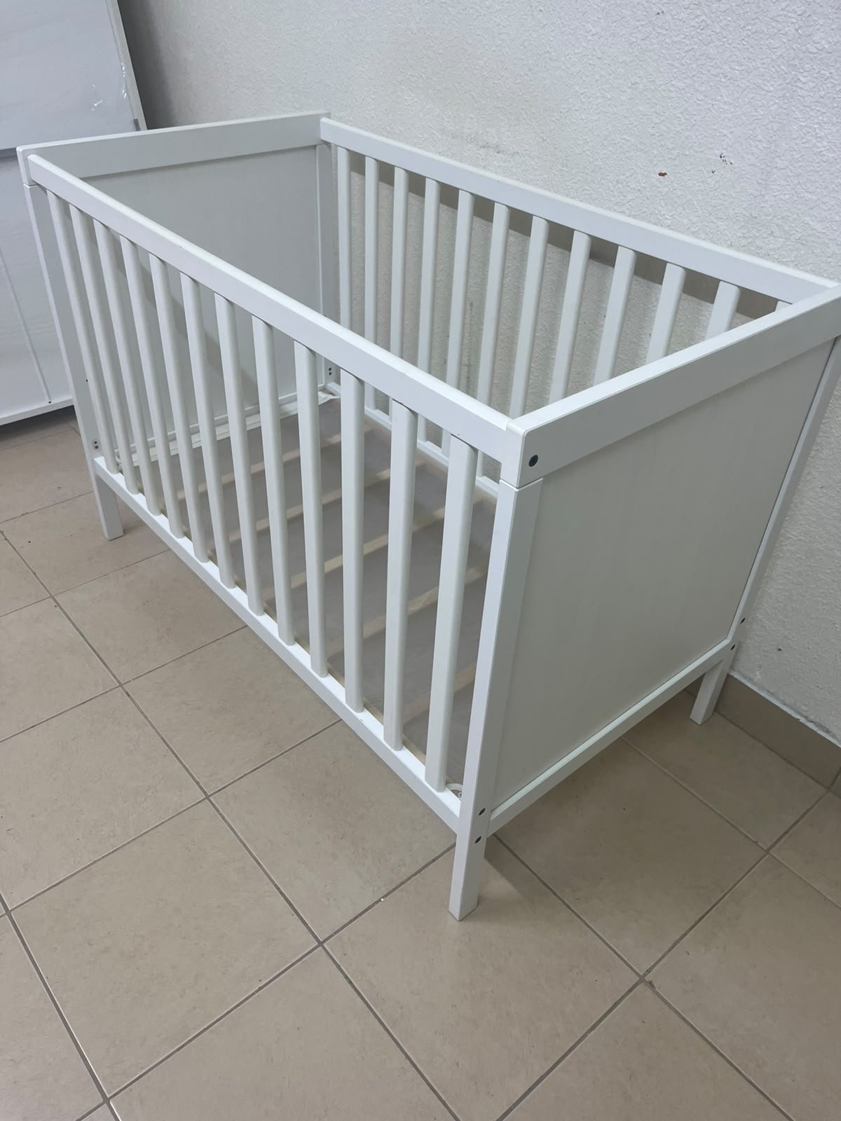 The white IKEA SUNDVIK crib (60x120 cm) features a sturdy wooden design and a bed base that can be adjusted to two different heights. - Image 7
