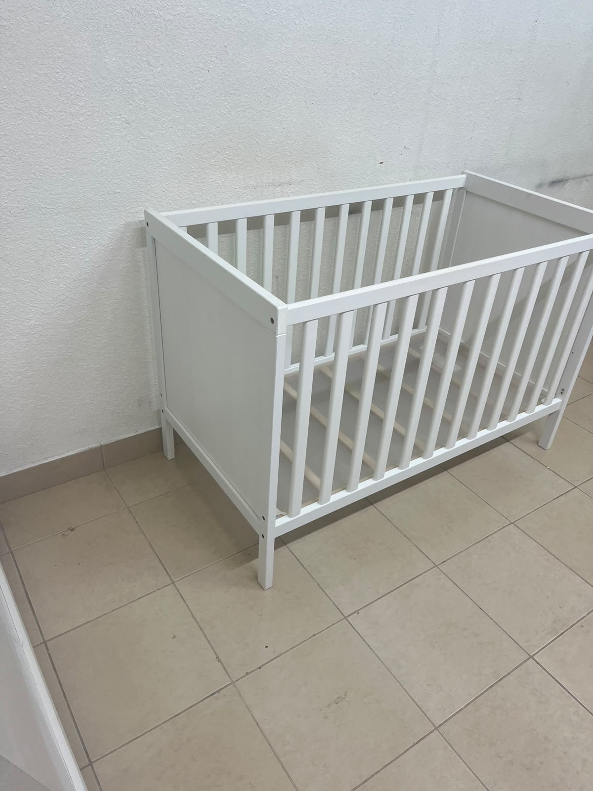 The white IKEA SUNDVIK crib (60x120 cm) features a sturdy wooden design and a bed base that can be adjusted to two different heights. - Image 8