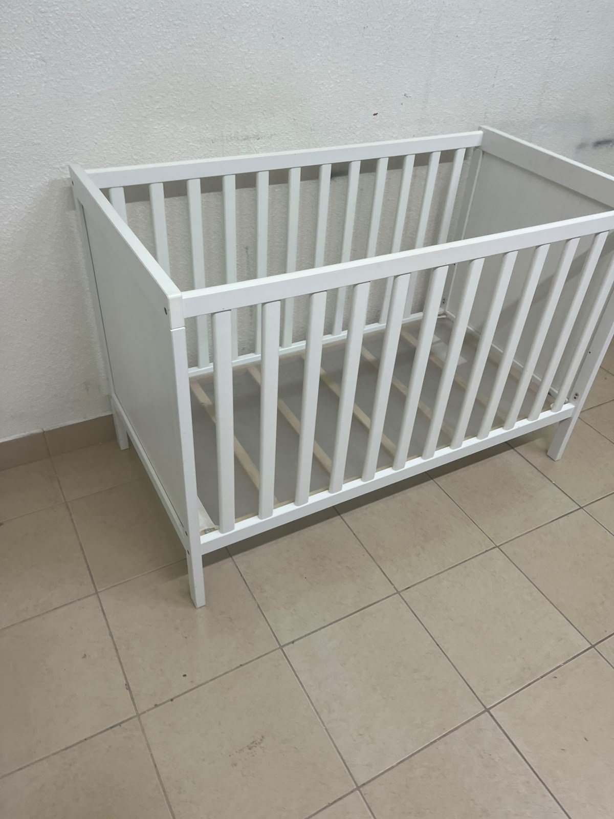 The white IKEA SUNDVIK crib (60x120 cm) features a sturdy wooden design and a bed base that can be adjusted to two different heights.