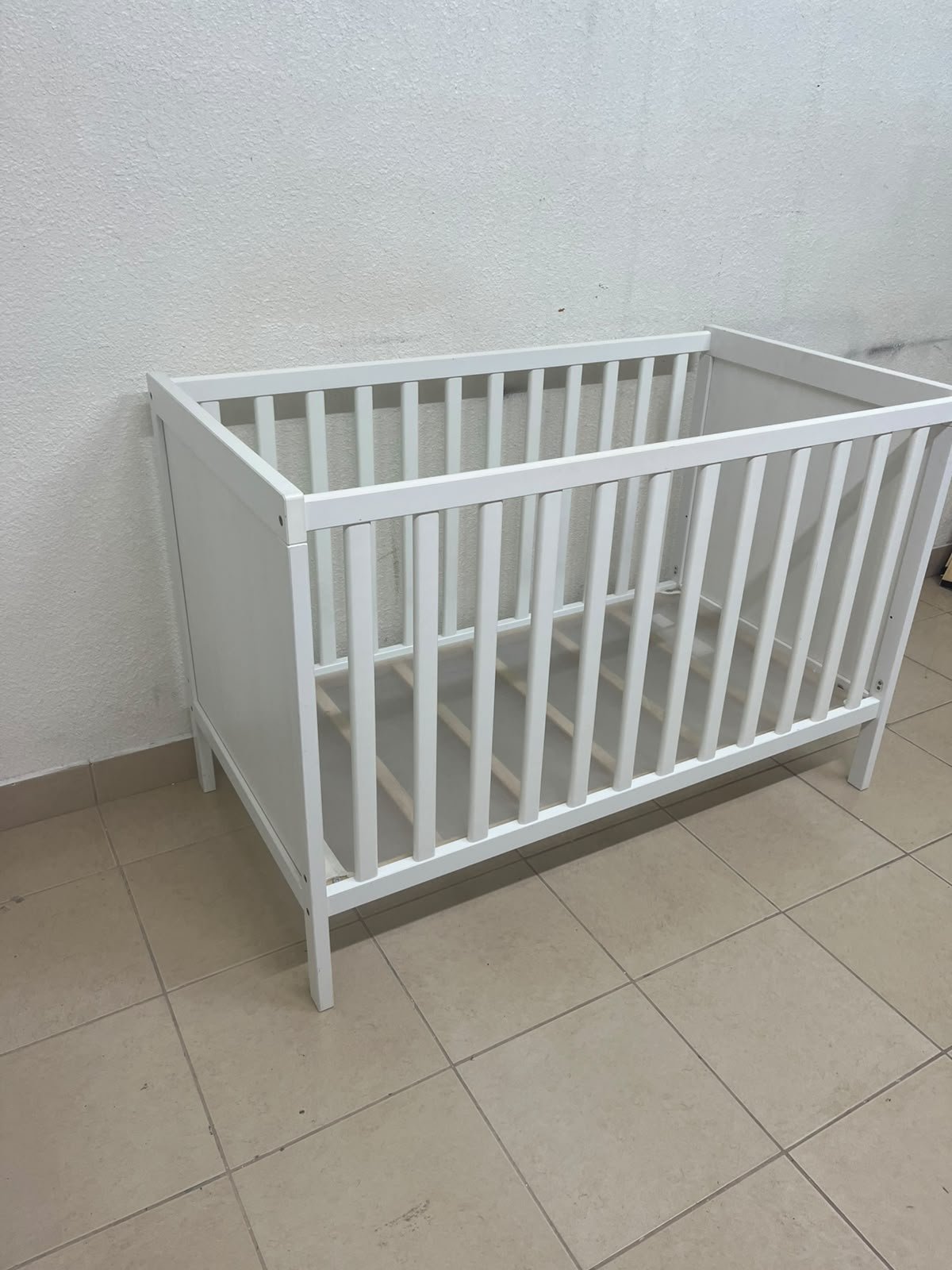 The white IKEA SUNDVIK crib (60x120 cm) features a sturdy wooden design and a bed base that can be adjusted to two different heights. - Image 11