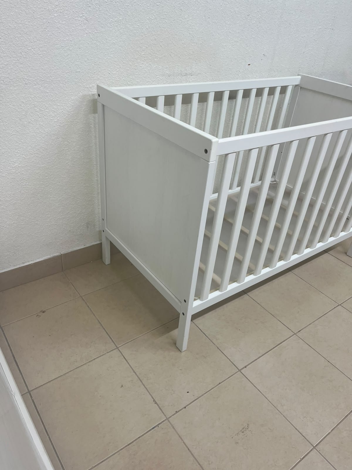 The white IKEA SUNDVIK crib (60x120 cm) features a sturdy wooden design and a bed base that can be adjusted to two different heights. - Image 12
