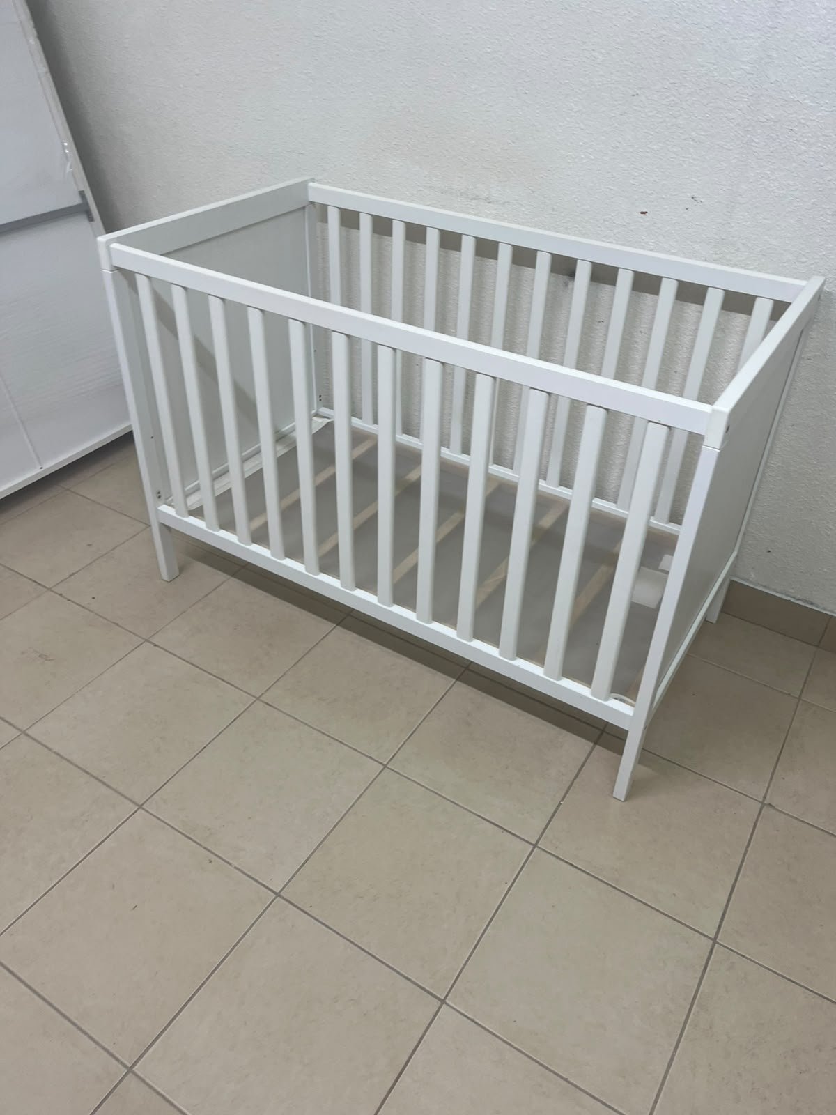 The white IKEA SUNDVIK crib (60x120 cm) features a sturdy wooden design and a bed base that can be adjusted to two different heights. - Image 13