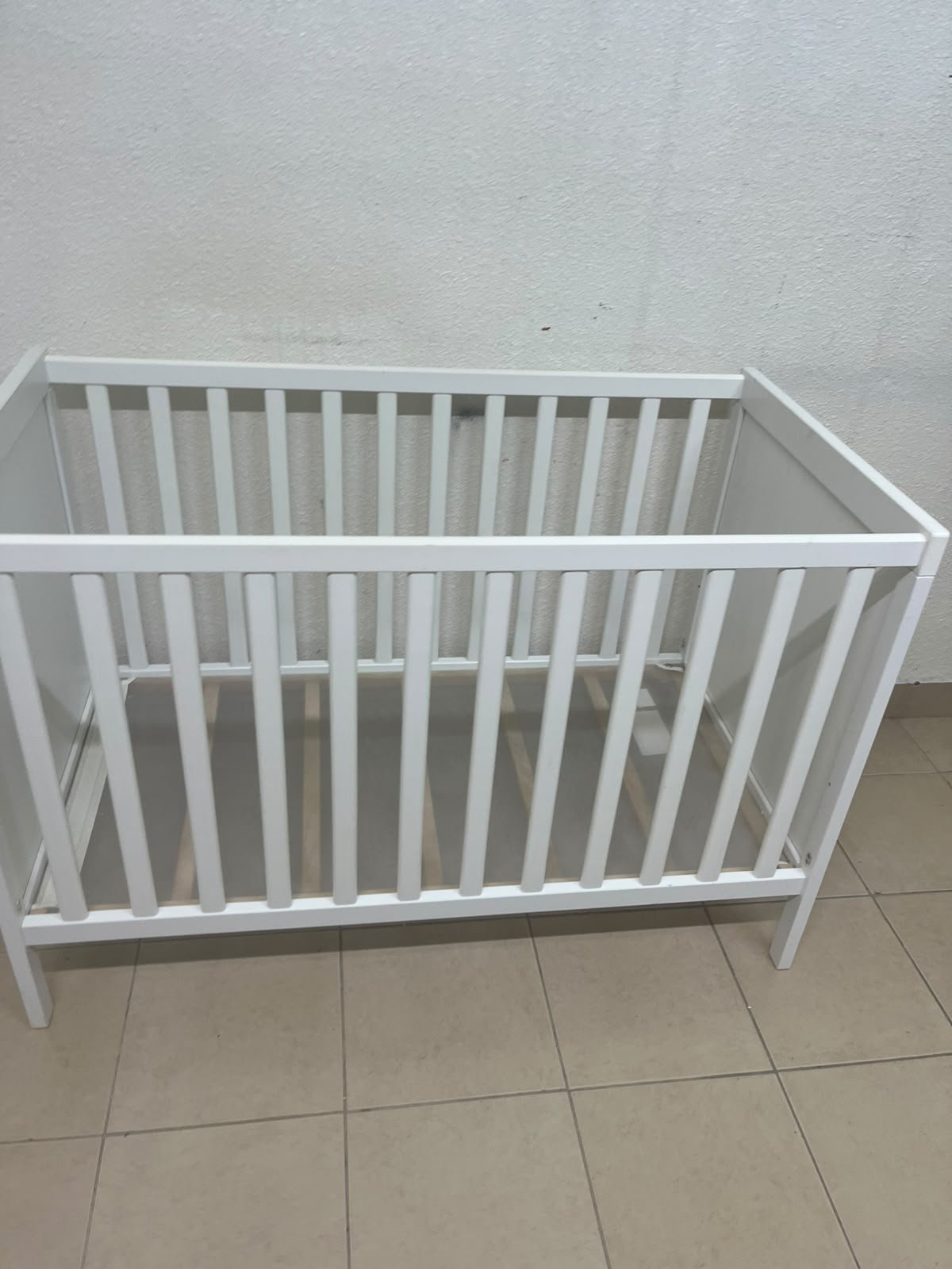 The white IKEA SUNDVIK crib (60x120 cm) features a sturdy wooden design and a bed base that can be adjusted to two different heights. - Image 2