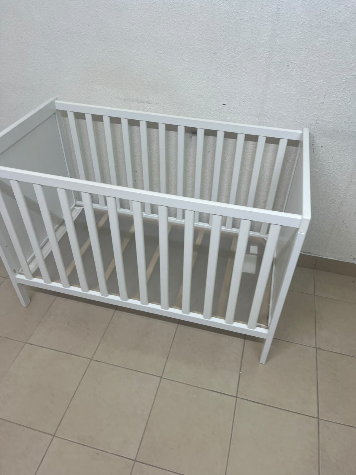 The white IKEA SUNDVIK crib (60x120 cm) features a sturdy wooden design and a bed base that can be adjusted to two different heights. - Image 4