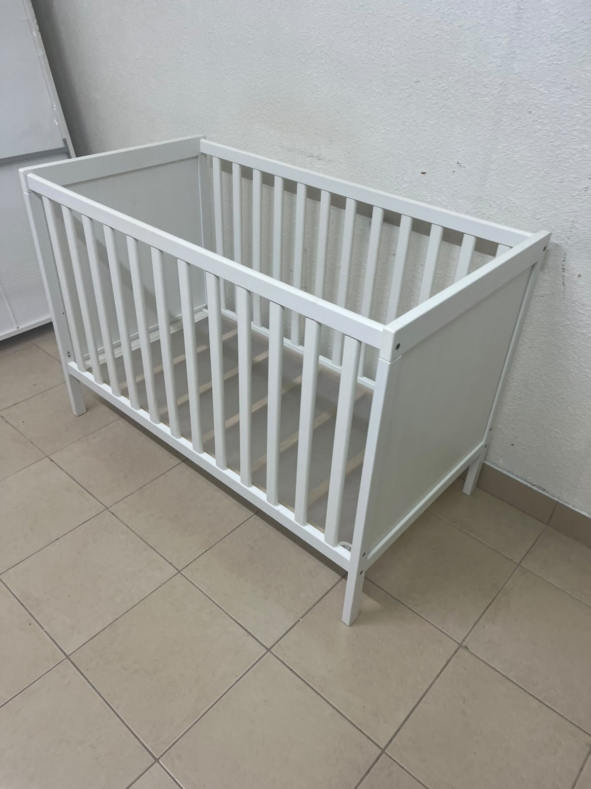 The white IKEA SUNDVIK crib (60x120 cm) features a sturdy wooden design and a bed base that can be adjusted to two different heights. - Image 5