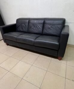 A modern three-seater black leather sofa featuring square armrests and wooden legs, resembling the IKEA "Skogaby" model.