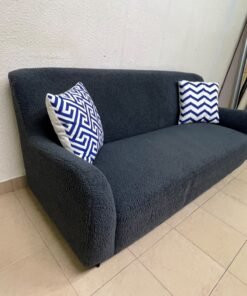 A dark blue, textured fabric sofa, adorned with two decorative cushions featuring patterns that combine blue and white. - Image 2