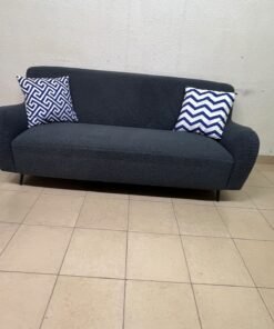 A dark blue, textured fabric sofa, adorned with two decorative cushions featuring patterns that combine blue and white. - Image 3