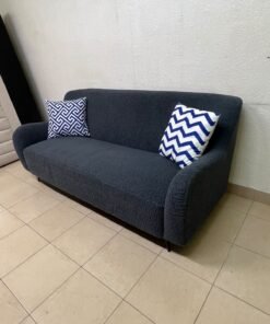 A dark blue, textured fabric sofa, adorned with two decorative cushions featuring patterns that combine blue and white. - Image 4