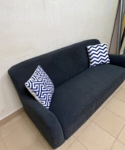 A dark blue, textured fabric sofa, adorned with two decorative cushions featuring patterns that combine blue and white. - Image 5