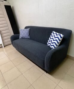 A dark blue, textured fabric sofa, adorned with two decorative cushions featuring patterns that combine blue and white. - Image 9