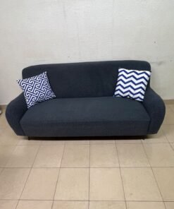 A dark blue, textured fabric sofa, adorned with two decorative cushions featuring patterns that combine blue and white. - Image 8