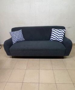 A dark blue, textured fabric sofa, adorned with two decorative cushions featuring patterns that combine blue and white. - Image 6