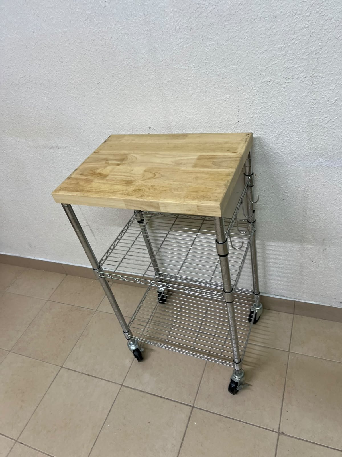 A multi-shelf kitchen cart made of chrome wire, featuring a light-colored wood top (butcher block style) and swivel casters. - Image 9