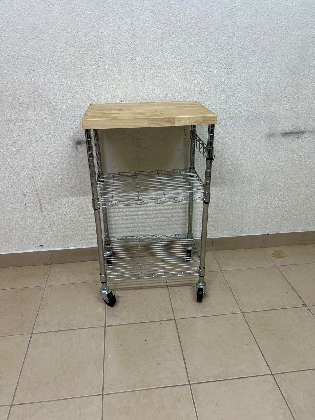 A multi-shelf kitchen cart made of chrome wire, featuring a light-colored wood top (butcher block style) and swivel casters. - Image 2
