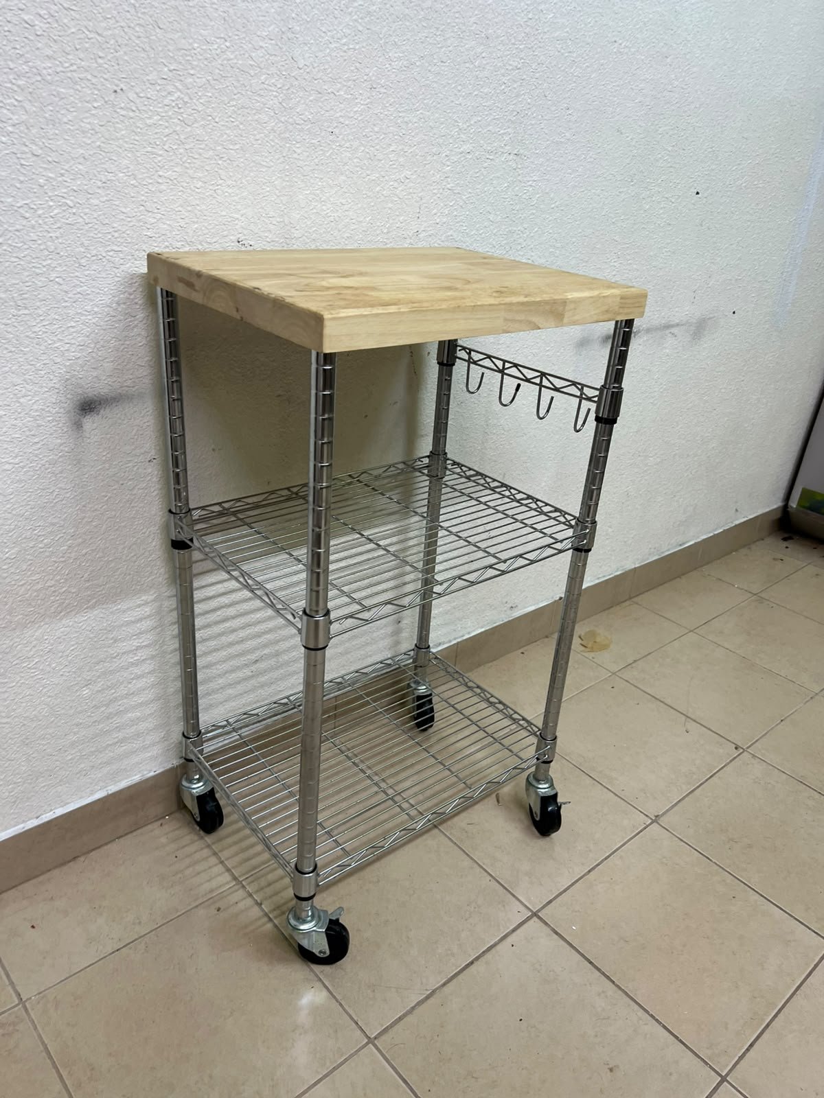 A multi-shelf kitchen cart made of chrome wire, featuring a light-colored wood top (butcher block style) and swivel casters. - Image 4