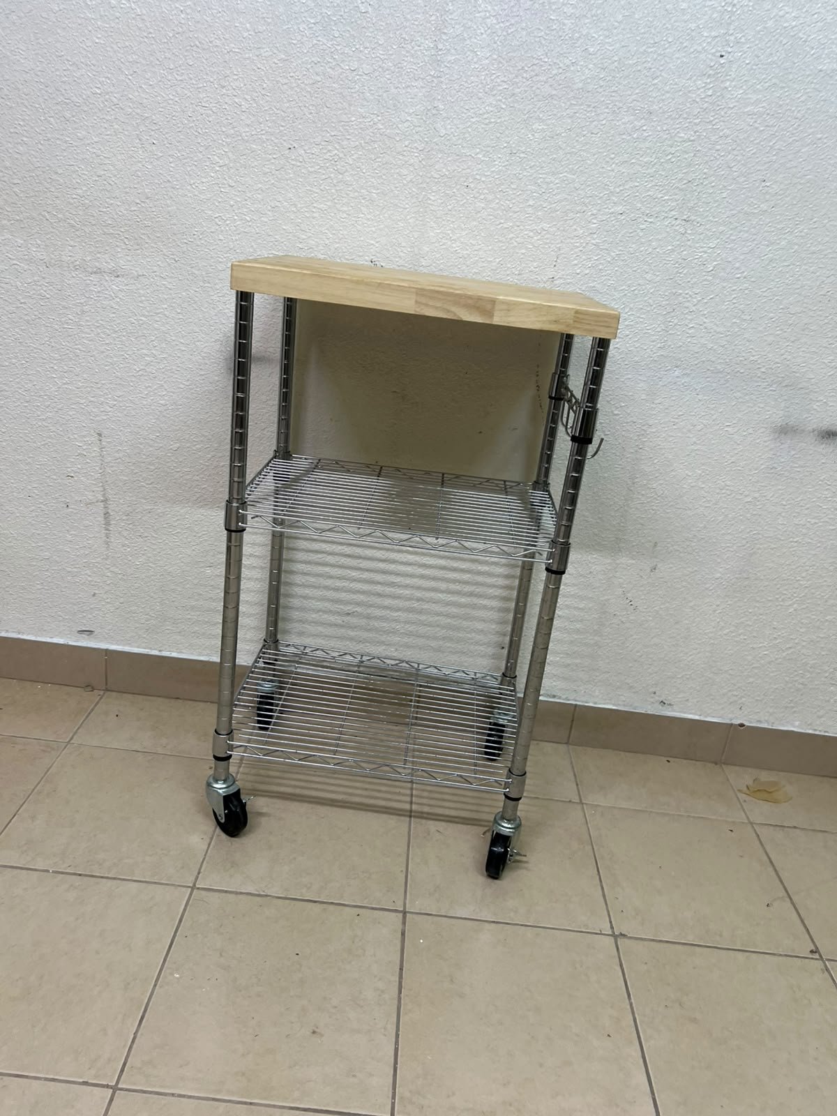 A multi-shelf kitchen cart made of chrome wire, featuring a light-colored wood top (butcher block style) and swivel casters. - Image 7