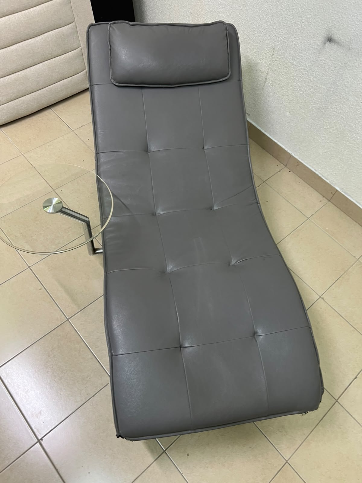 A modern grey faux leather chaise longue featuring an attached round glass side table and metal legs. - Image 3