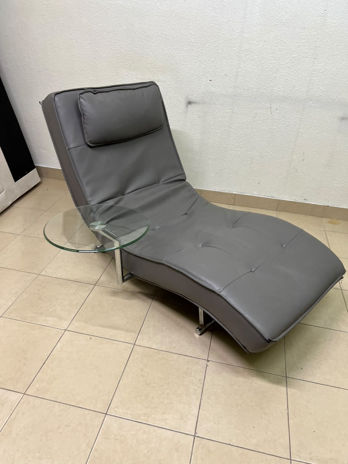 A modern grey faux leather chaise longue featuring an attached round glass side table and metal legs. - Image 4