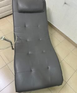 A modern grey faux leather chaise longue featuring an attached round glass side table and metal legs. - Image 5