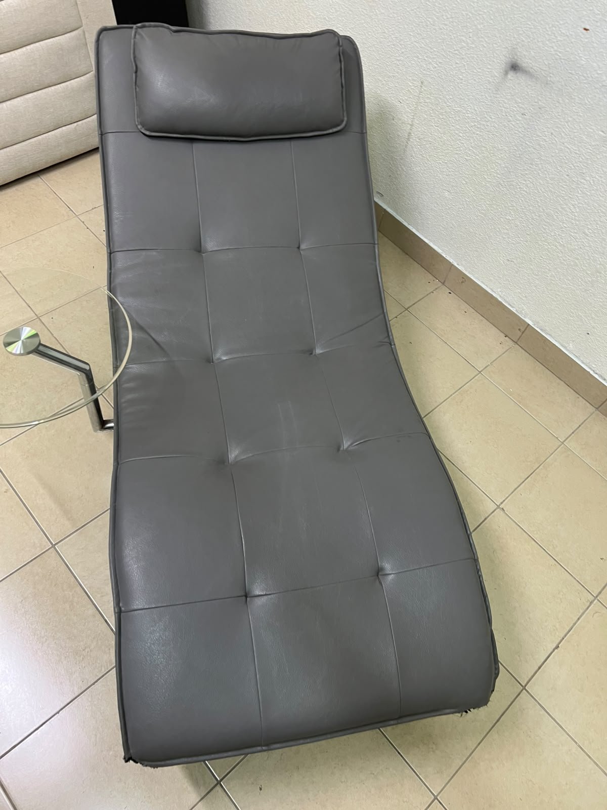 A modern grey faux leather chaise longue featuring an attached round glass side table and metal legs. - Image 5