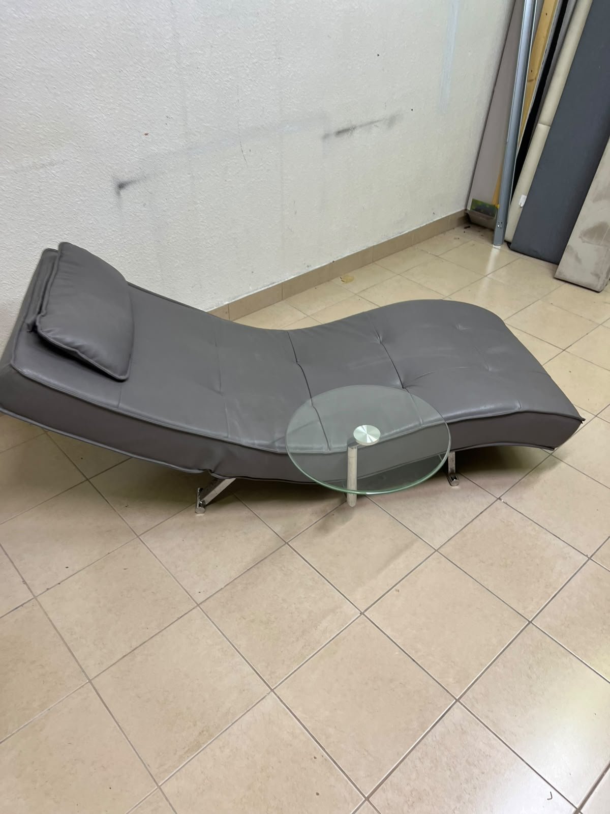 A modern grey faux leather chaise longue featuring an attached round glass side table and metal legs. - Image 6