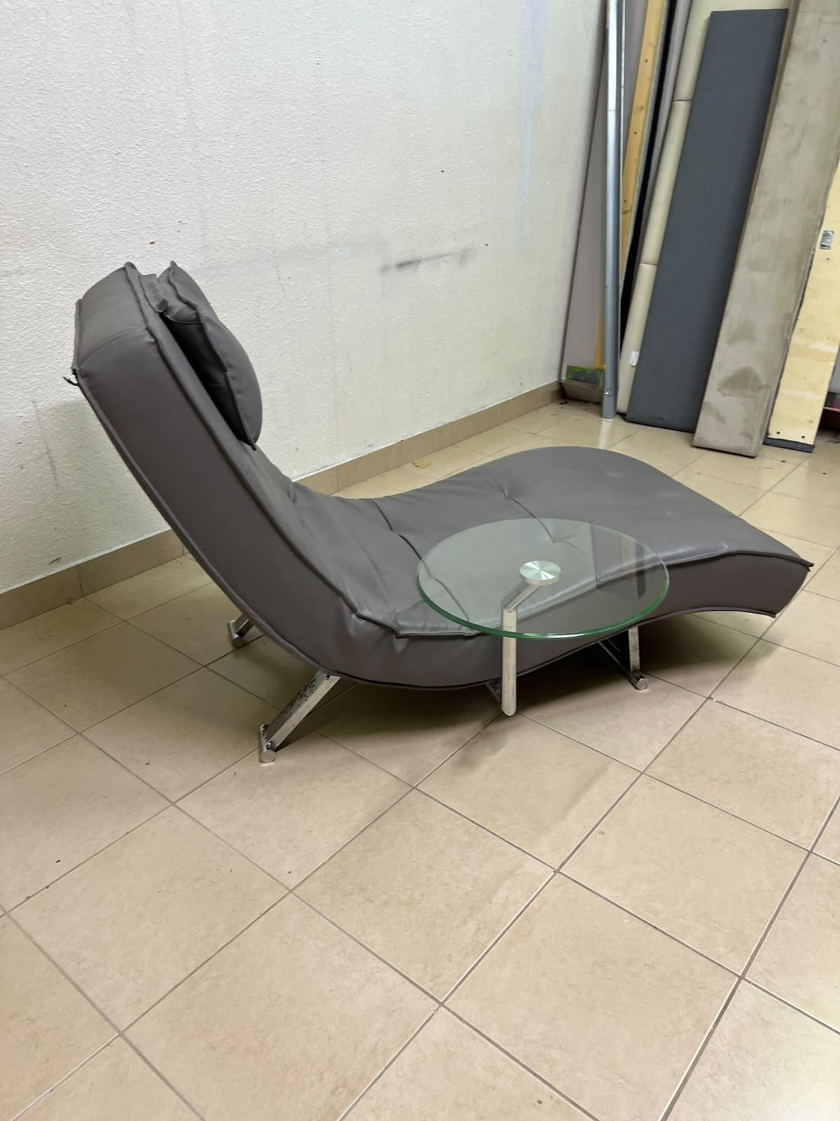 A modern grey faux leather chaise longue featuring an attached round glass side table and metal legs. - Image 7