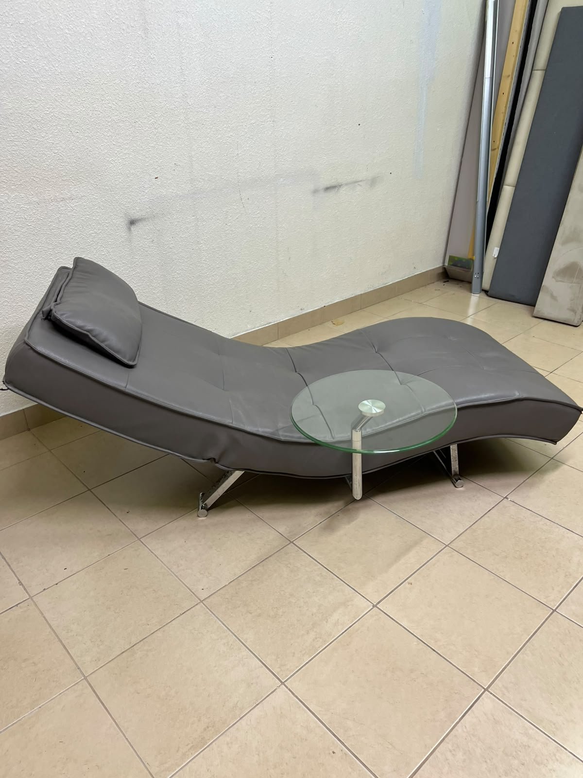 A modern grey faux leather chaise longue featuring an attached round glass side table and metal legs. - Image 8