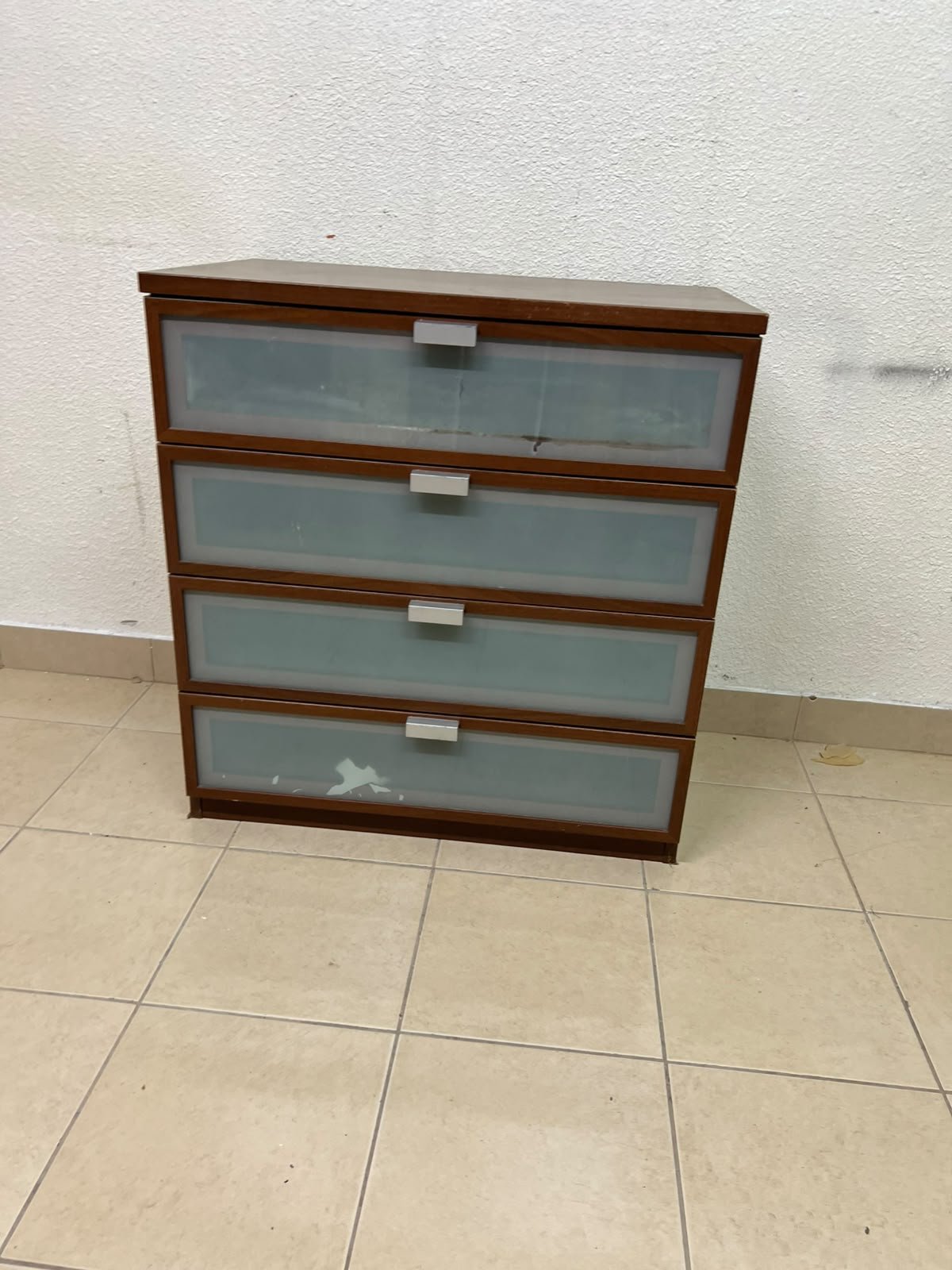 The IKEA HOPEN dark wood chest of drawers features four drawers with frosted glass fronts and silver-colored handles.