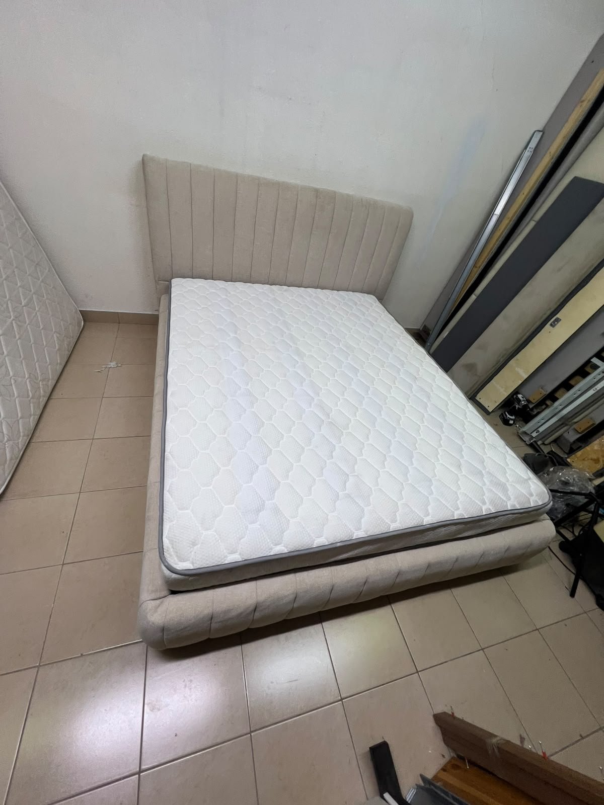 A bed featuring a modern design and a beige upholstered frame, complete with a headboard designed with padded vertical channels and a matching upholstered base; its style resembles the "Curvy Haze" upholstered bed available at Home Box. - Image 8