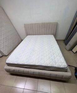 A bed featuring a modern design and a beige upholstered frame, complete with a headboard designed with padded vertical channels and a matching upholstered base; its style resembles the "Curvy Haze" upholstered bed available at Home Box. - Image 10