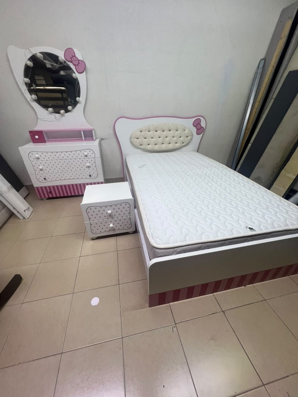 A girls' bedroom featuring a white and pink color scheme, including a bed with bedding, a storage table with an illuminated mirror, and a bedside table. - Image 3