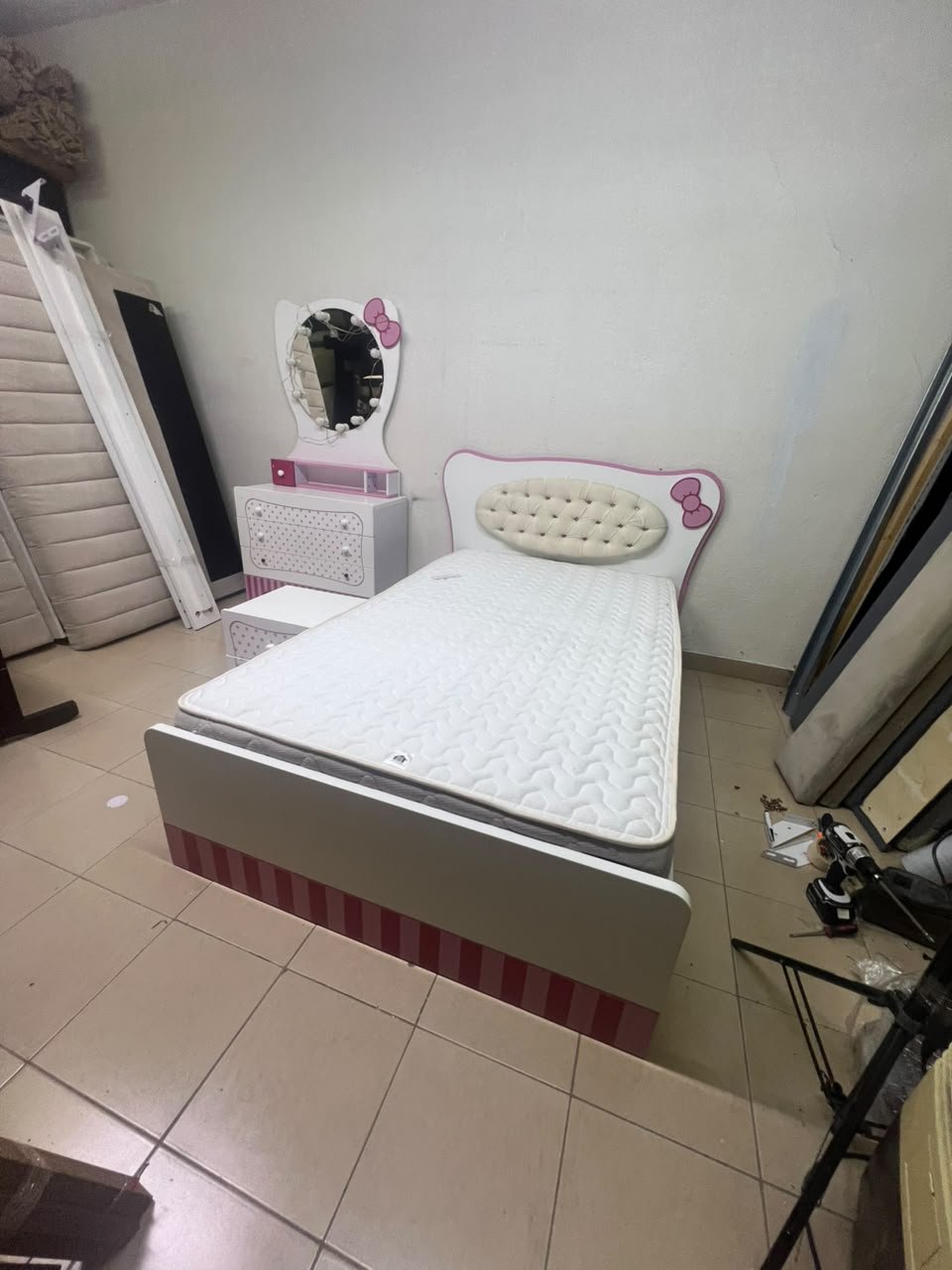 A girls' bedroom featuring a white and pink color scheme, including a bed with bedding, a storage table with an illuminated mirror, and a bedside table. - Image 5